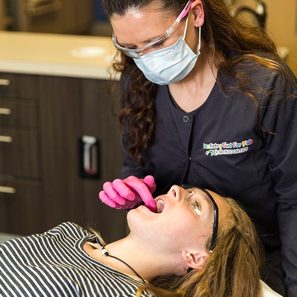 Orthodontic assistant checking patient's braces.