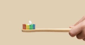 Someone holding a rainbow toothbrush with kid's toothpaste