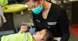 A pediatric dentist looking at a child's first adult teeth